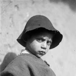 7. Niño con poncho y sombrero jugando con un runrún.
