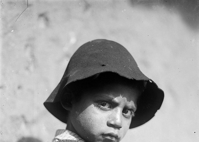 7. Niño con poncho y sombrero jugando con un runrún.