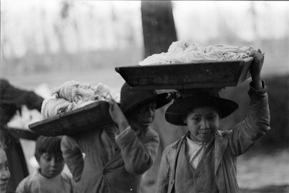 4. Niños cargan bateas con ropa lavada.