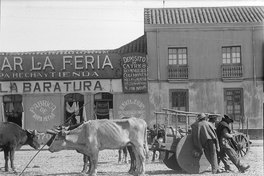 10. Tres hombres con sus animales de carga y carretas en la feria.