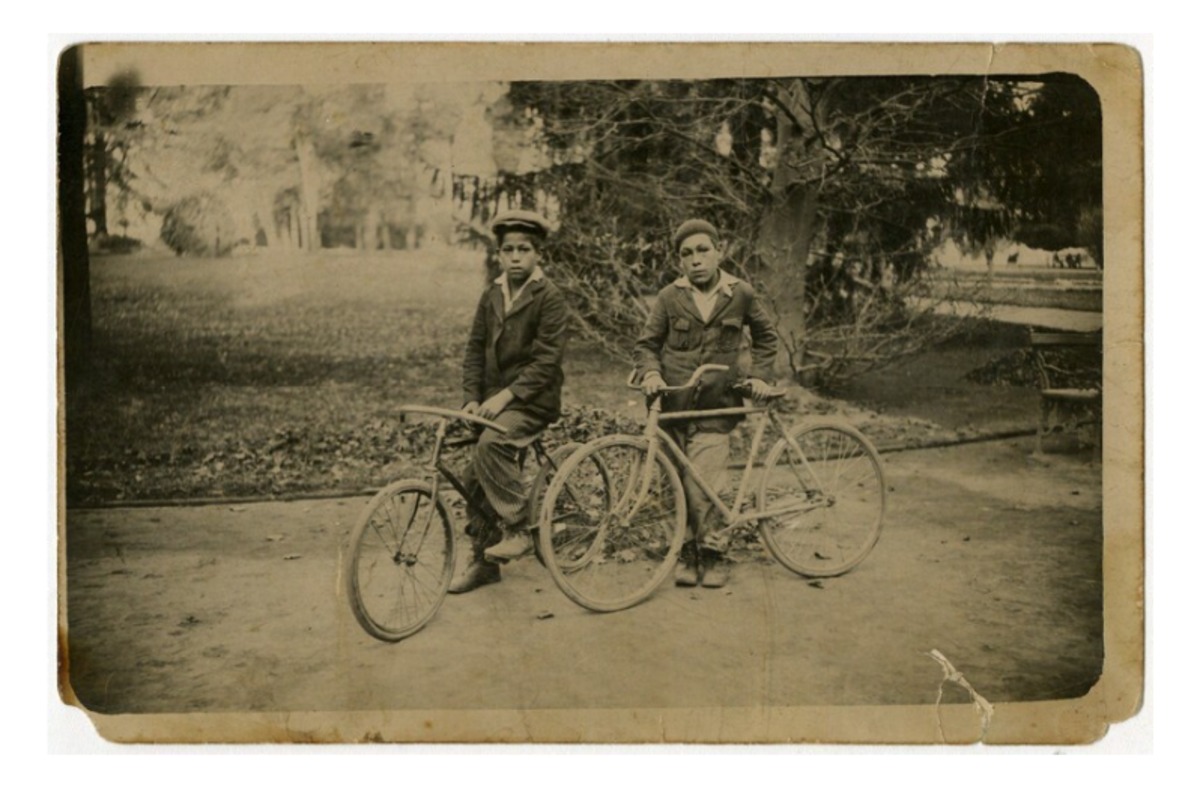 3. Dos niños con boinas, aparecen en la fotografía en bicicleta en el parque de la Quinta Normal.