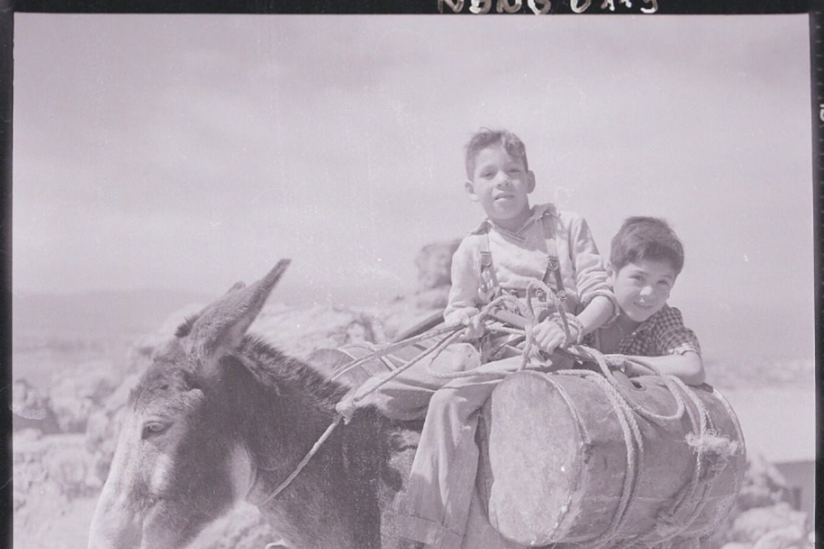 8. Dos niños de pies descalzos, montan un burro que lleva carga. Fotografía de Ignacio Hochhäusler, entre 1949 y 1960.